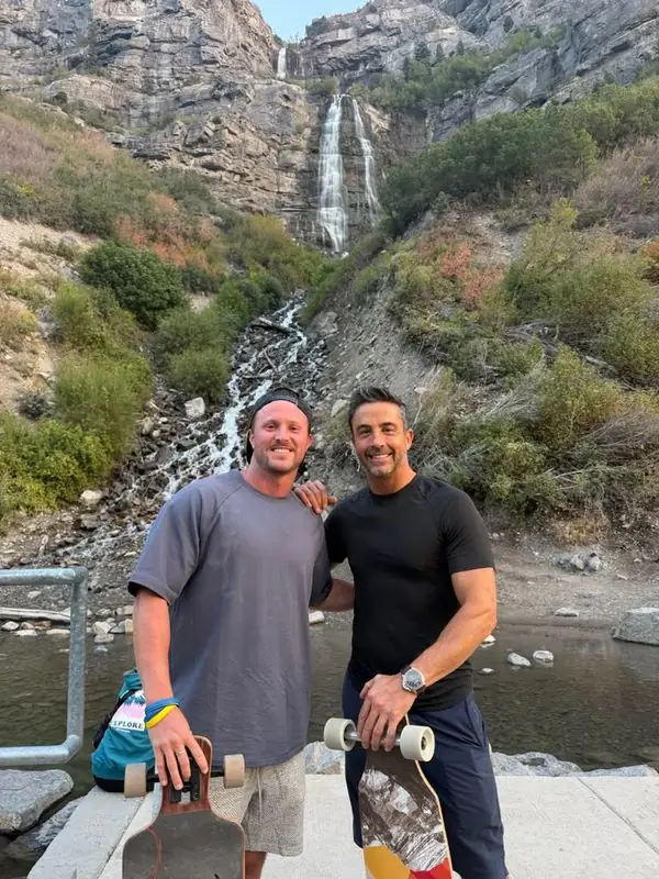 Travis and friend with longboards below mountain waterfall