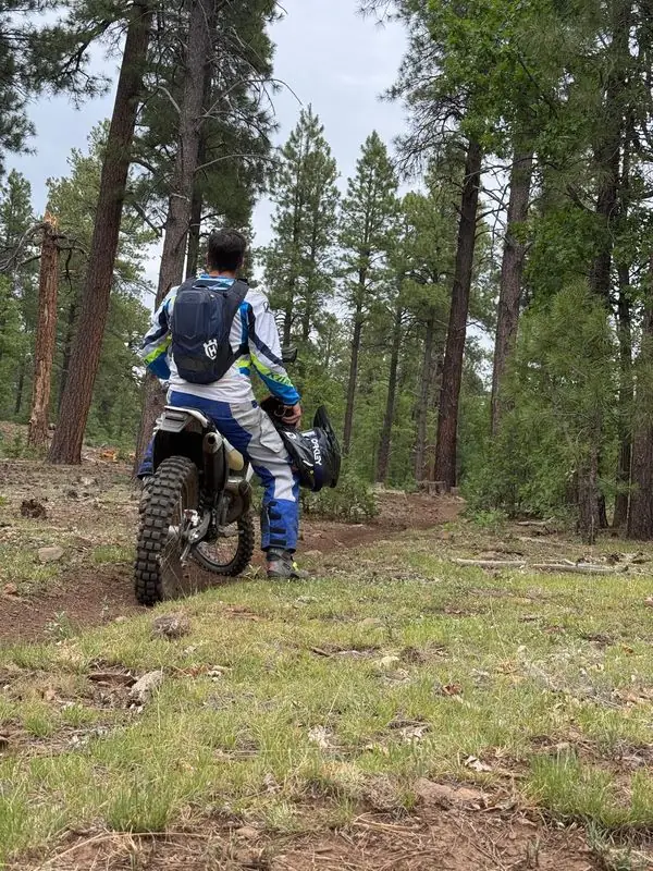 Travis on dirt bike pausing on pine forest trail