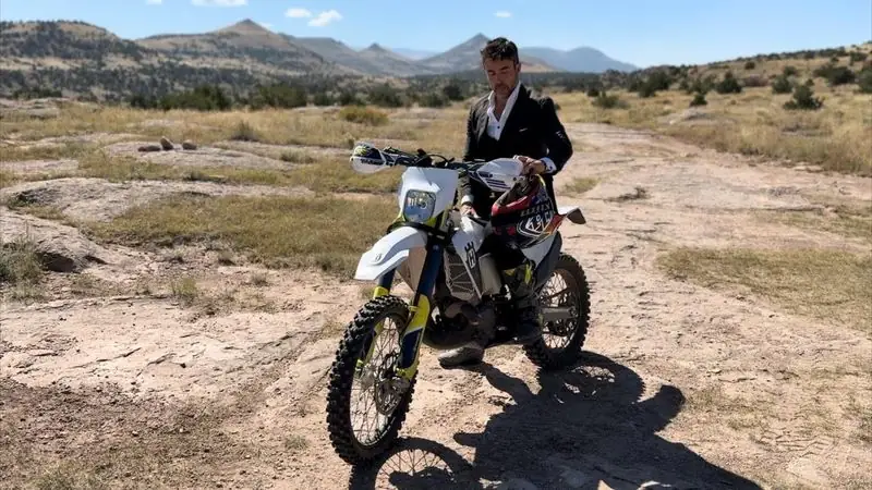 Suit jacket astride dirt bike on desert track