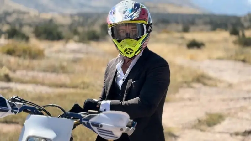 Travis in suit and motocross helmet on dirt bike