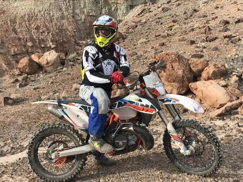Geared rider posed on KTM dirt bike in rocky desert