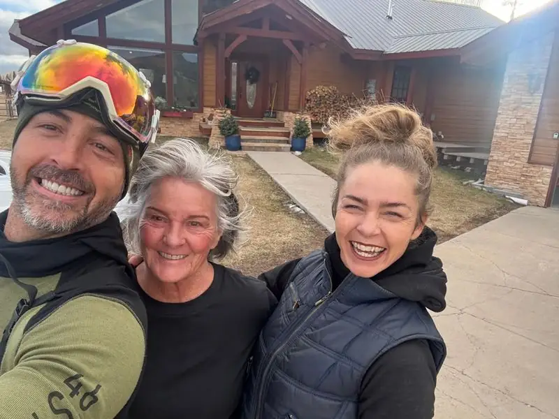 Ski-goggle selfie with mother and sister outside mountain home