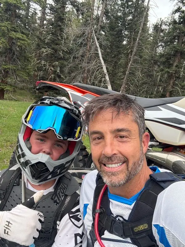 Selfie with son in motocross helmet, forest