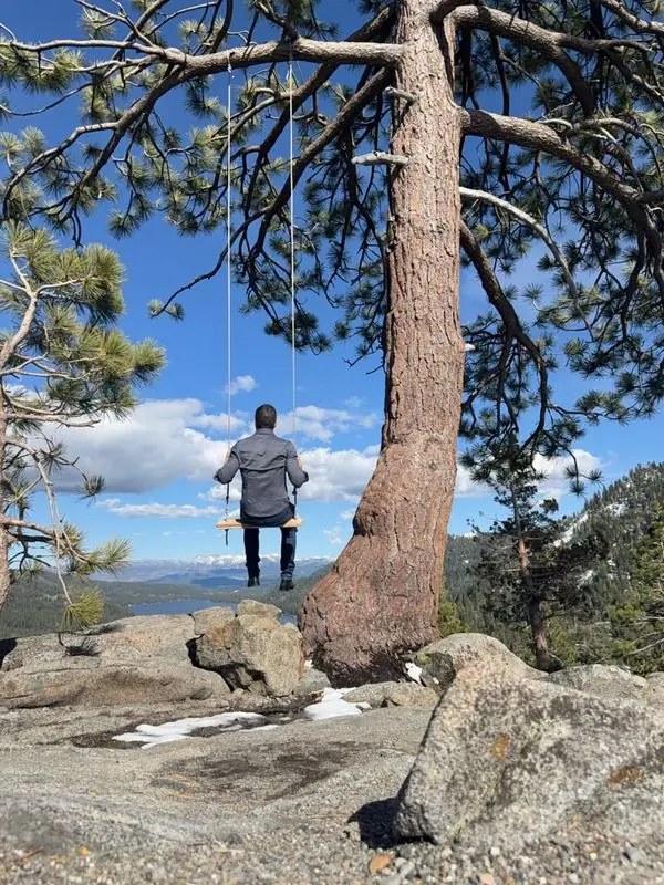 Travis on tree swing overlooking lake and snowy mountains