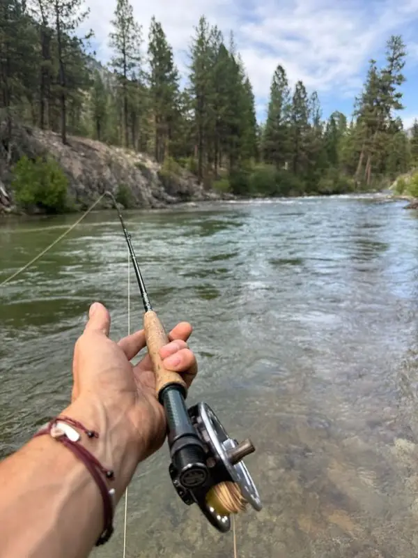 First-person fly fishing rod over clear mountain river