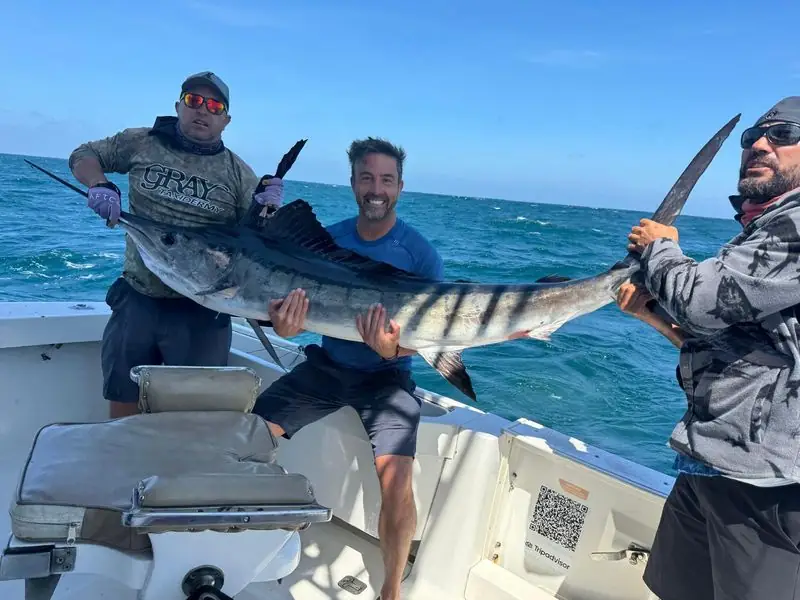 Travis holding striped marlin on boat with crew