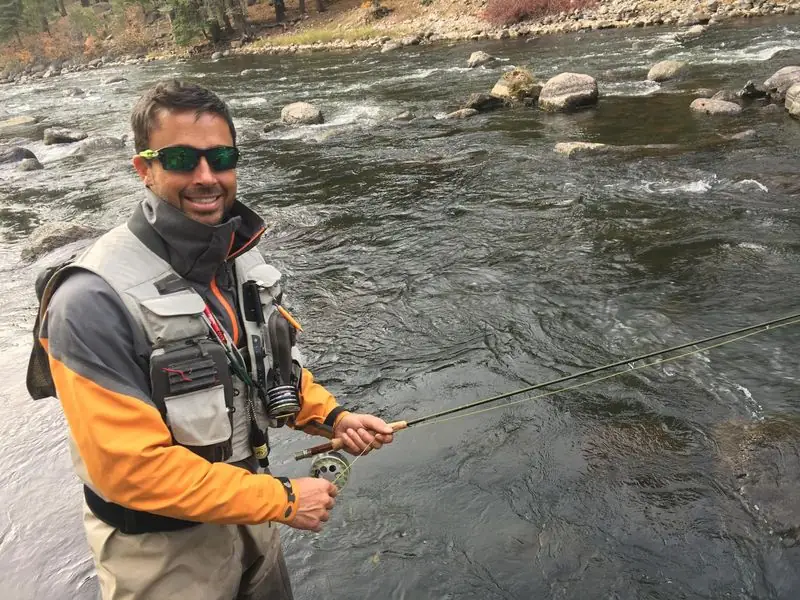 Fly fishing rocky river in waders, smiling