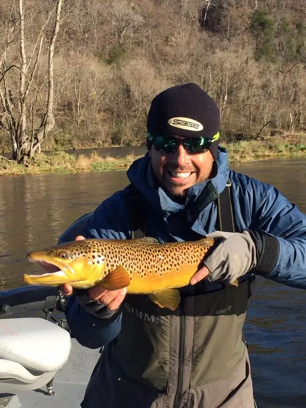Travis in waders holding large brown trout riverside