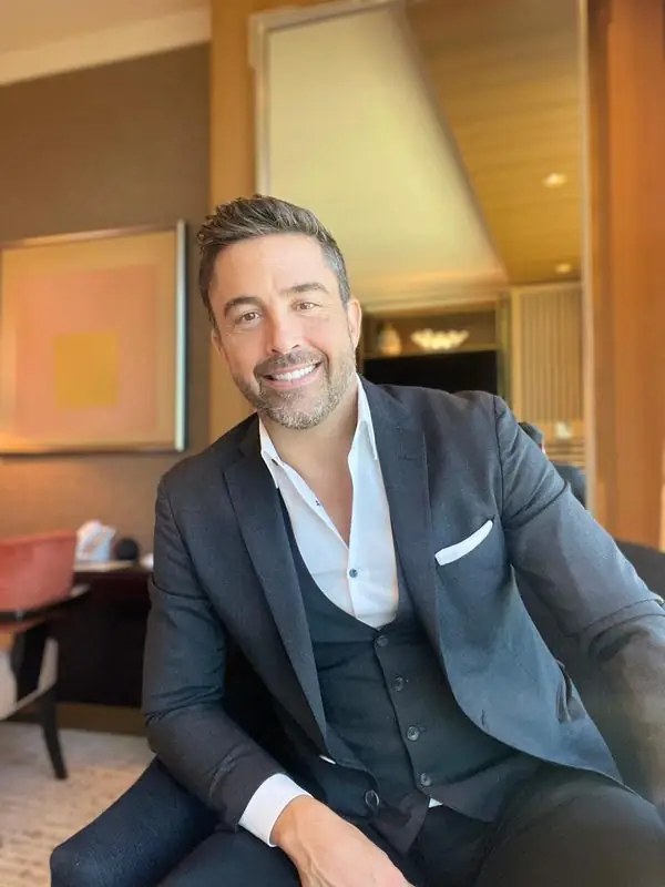 Smiling seated portrait in three-piece suit, upscale interior