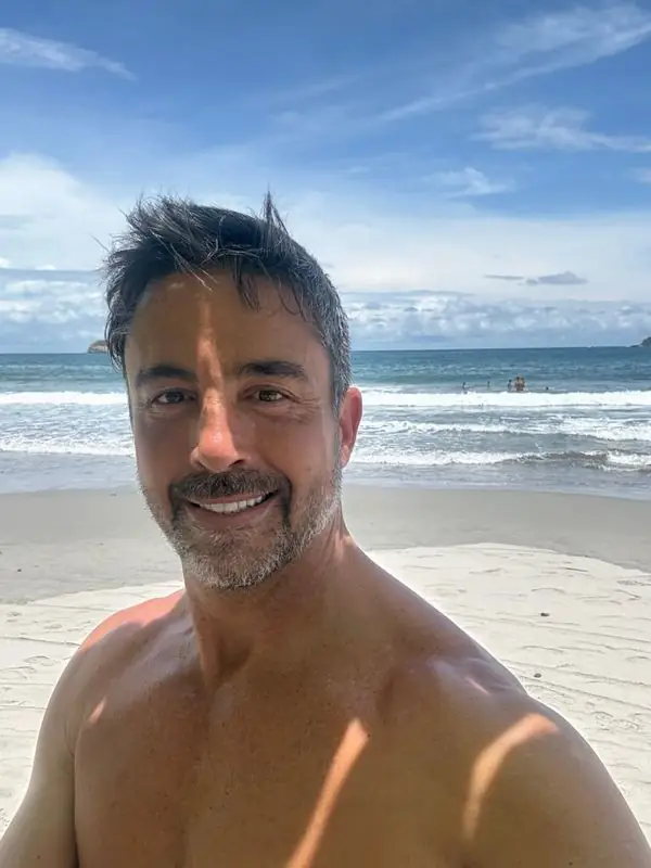Shirtless beach selfie with ocean surf behind