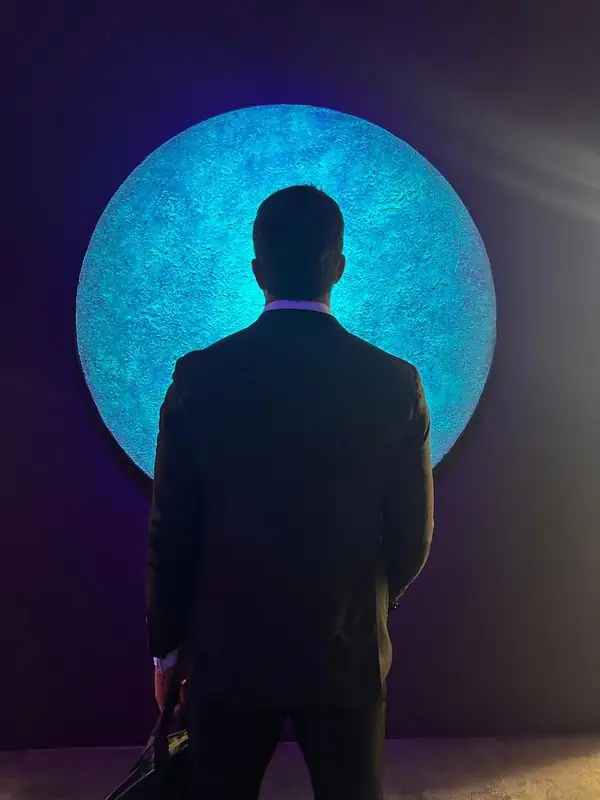 Silhouetted Travis facing glowing blue circular art installation