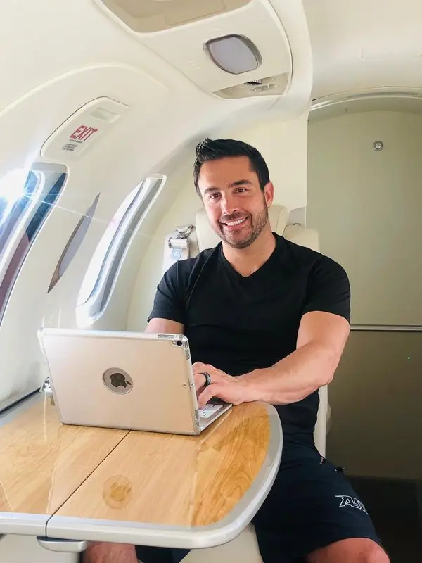 Travis smiling with iPad at private jet table