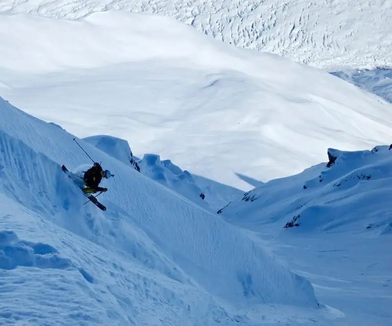 Backcountry skier charging powder on steep glacier face