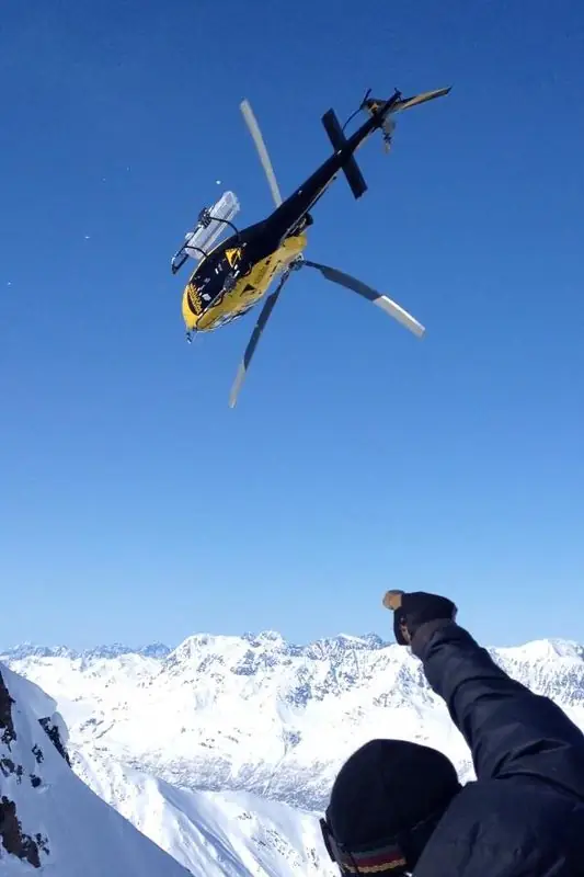 Heli-ski drop-off, fist raised at departing helicopter