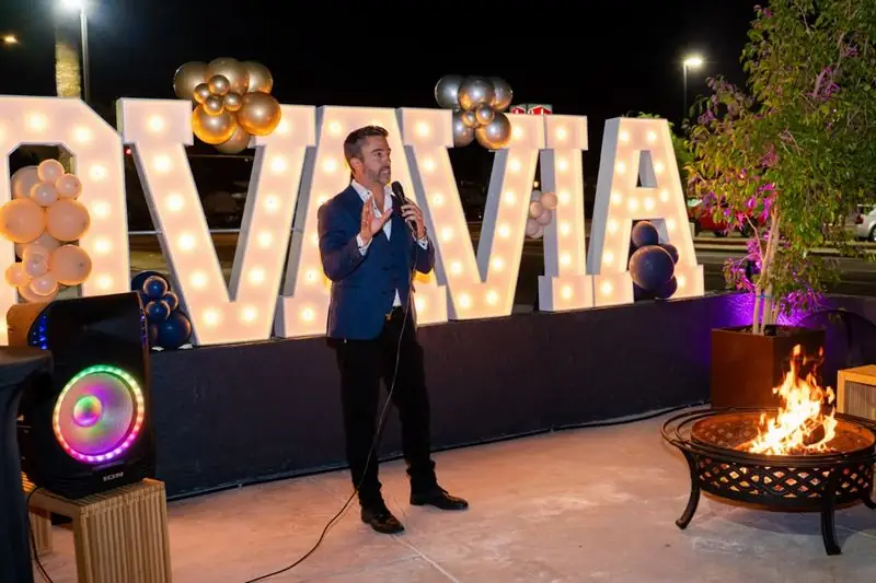 Travis speaking with mic at NOVAVIA marquee-letter event