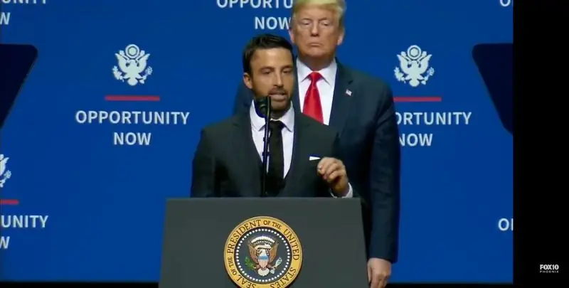 Travis speaking at podium with Trump at Opportunity Now event