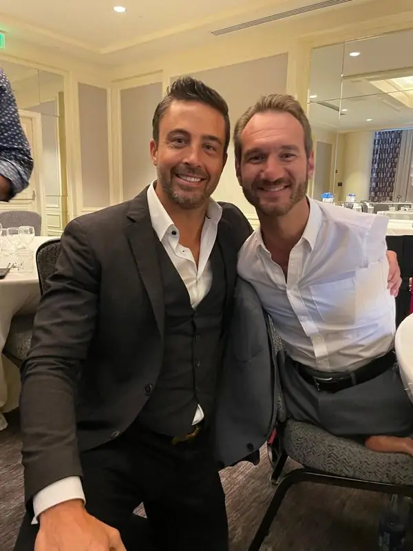Travis with Nick Vujicic smiling at banquet event