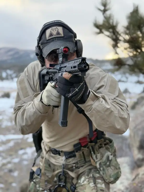 Travis aiming braced pistol rifle with red optic, winter range